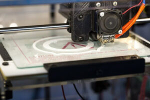 A black medium-sized machine printing a white design on a glass platform
